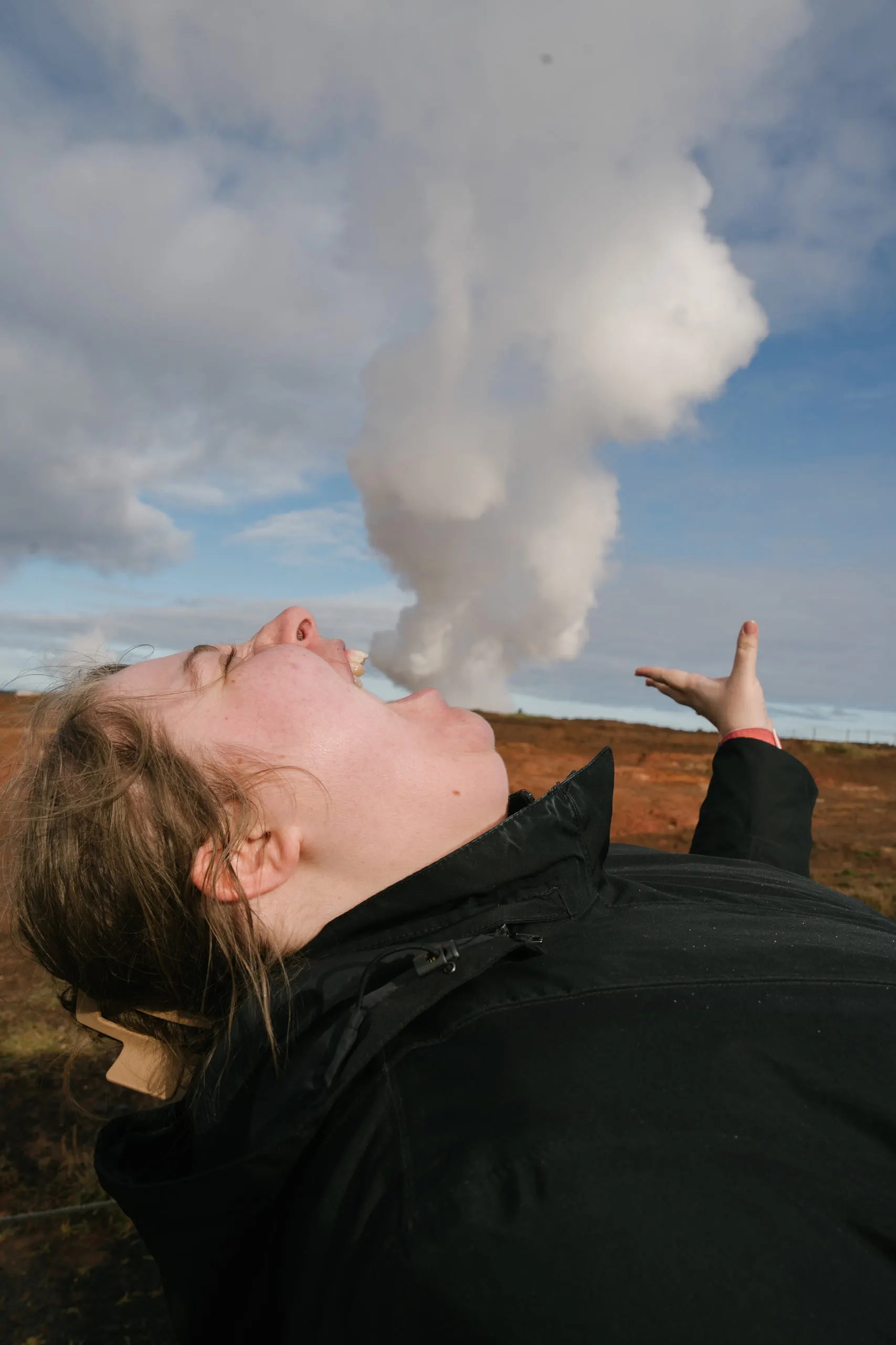 Kylie tilting her head back with one arm outstretched, lining herself up with a steam plume rising behind her.
