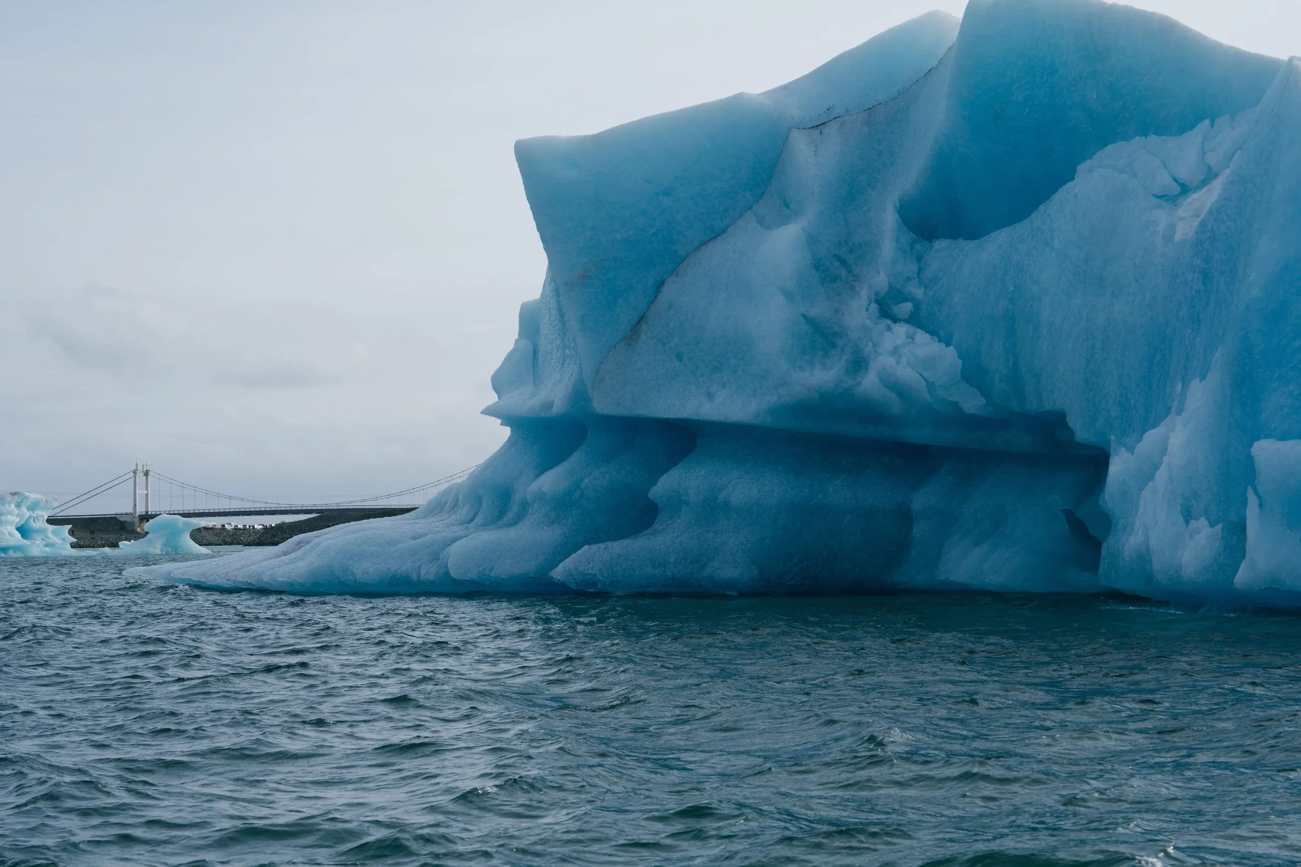 A large iceberg with a deep blue arch of compressed ice at its base.