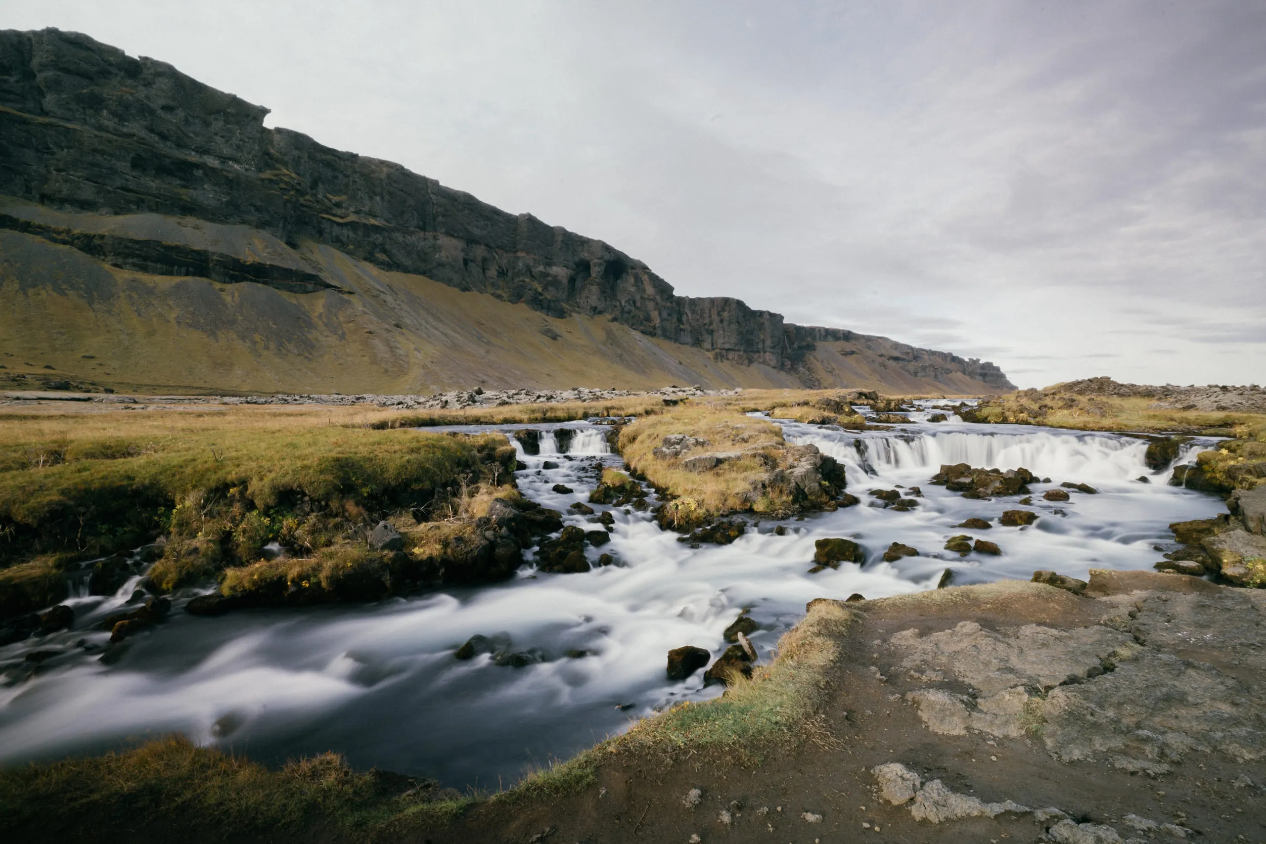 A braided stream at a long exposure, the water smoothed into white ribbons over dark rock.