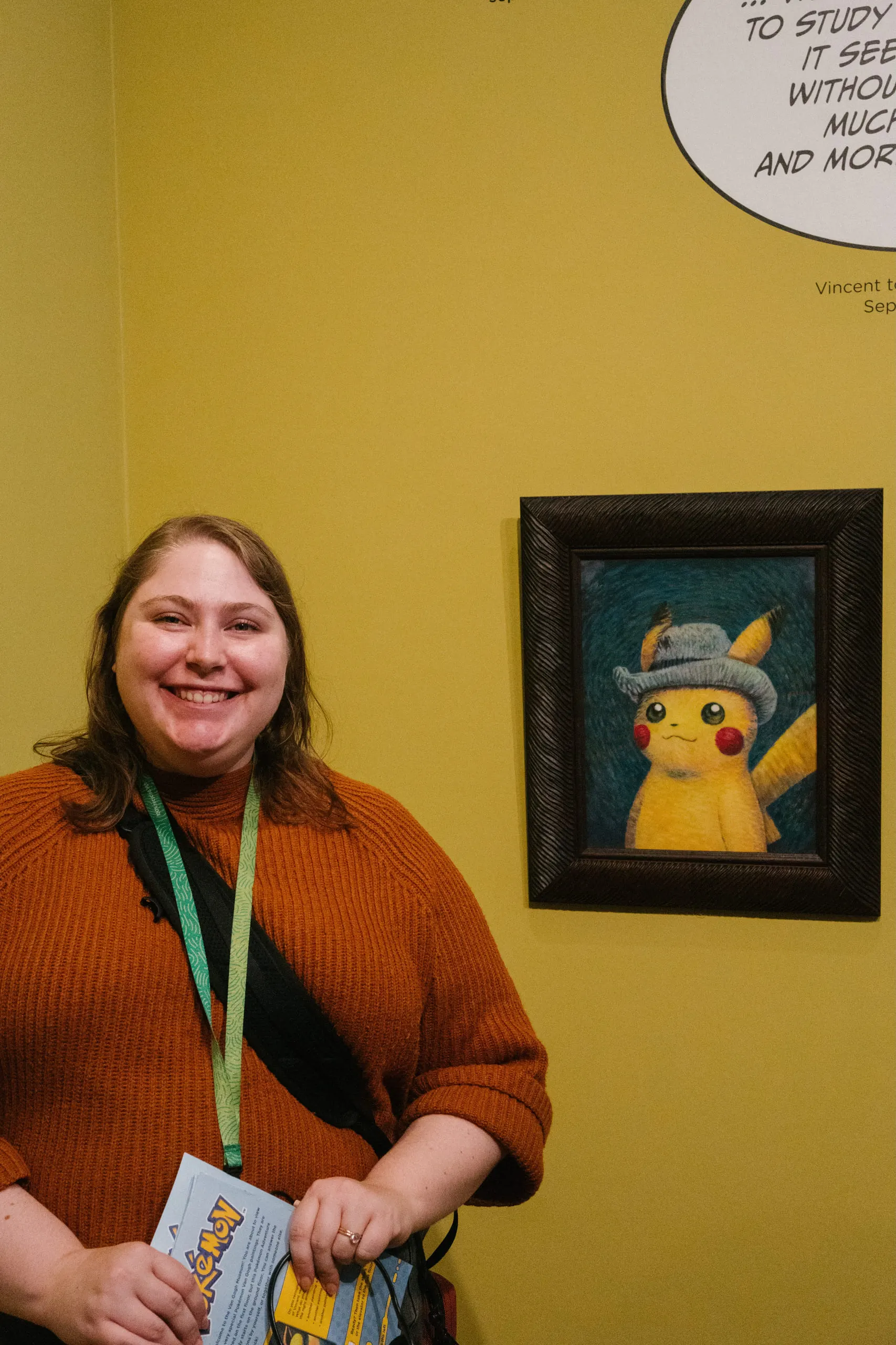 Kylie standing beside a small framed painting of Pikachu rendered in the style of a Van Gogh self-portrait.