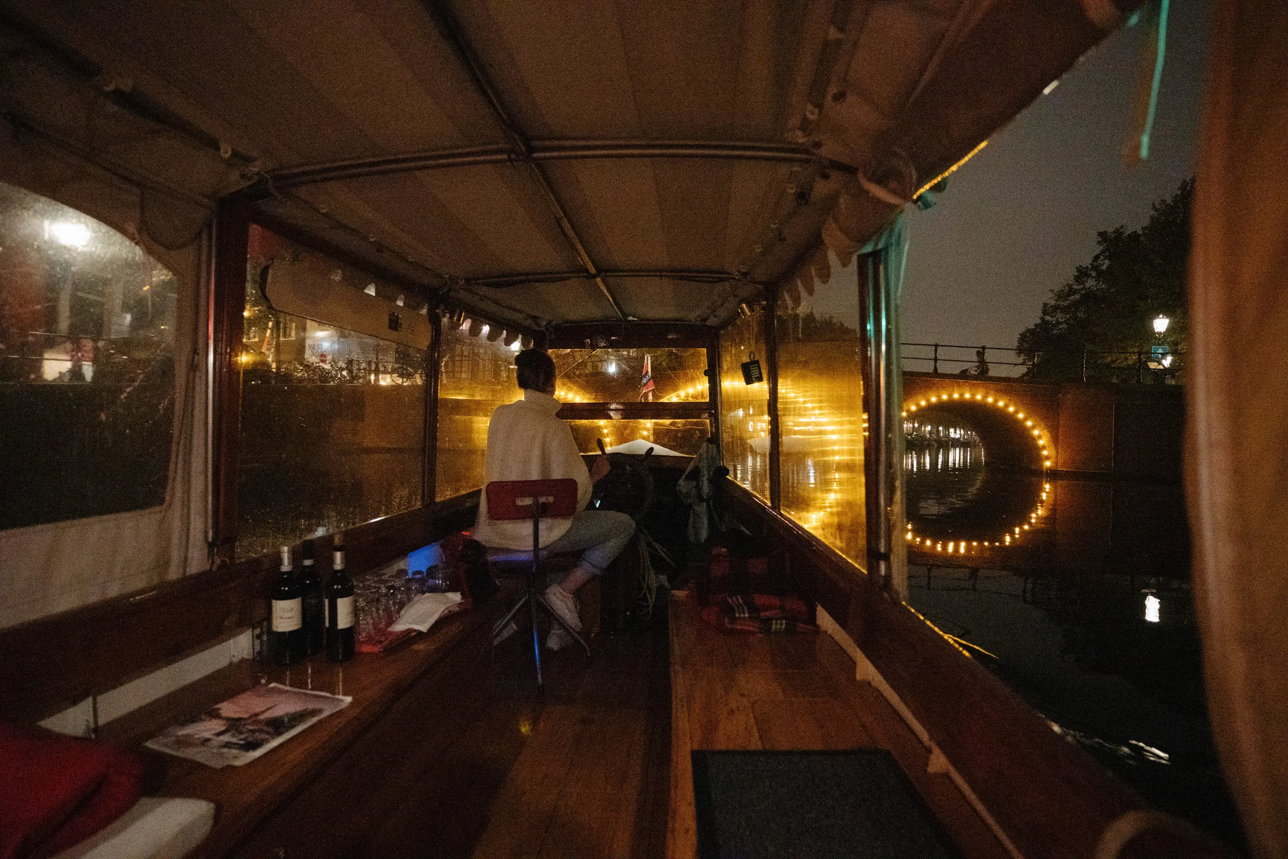 The long wood-panelled interior of a canal boat set for dinner, string lights running along the ceiling.